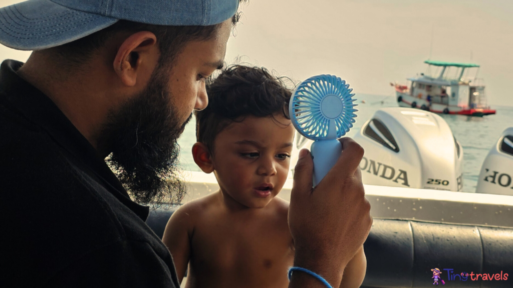 On Thr way to Koh Nang Yuan. Dad holding portable fan during extreme hot and humid weather in Thailand 